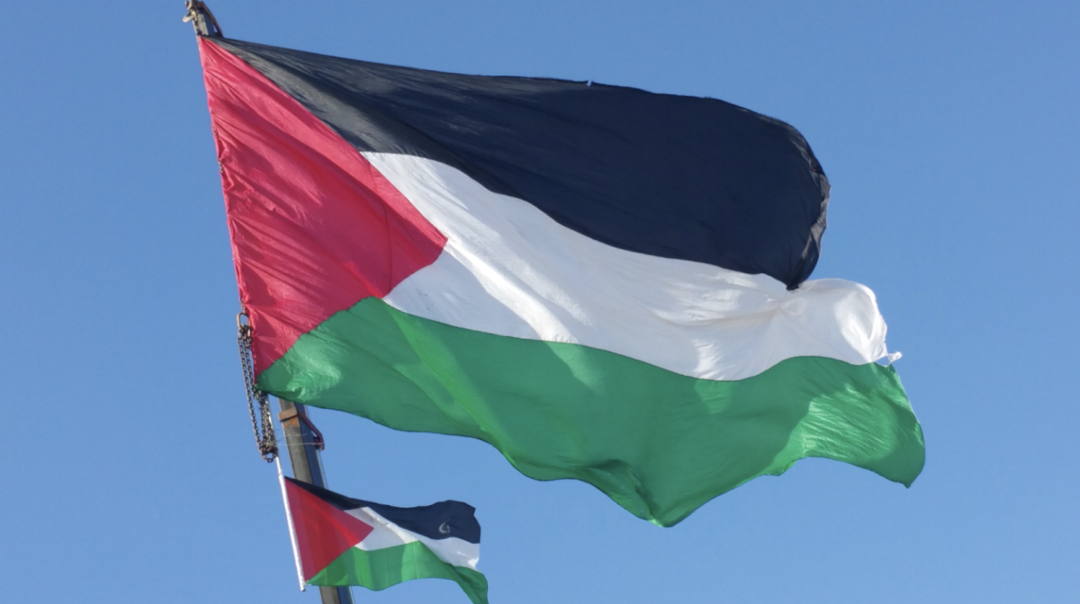 Palestinian flag waving in the air with a smaller Palestinian flag below it.